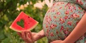 vannmelonskive i hånden til en gravid kvinne